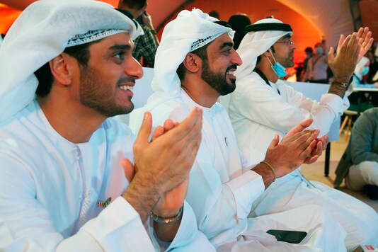 Emirati men claps as they watch the launch of the 