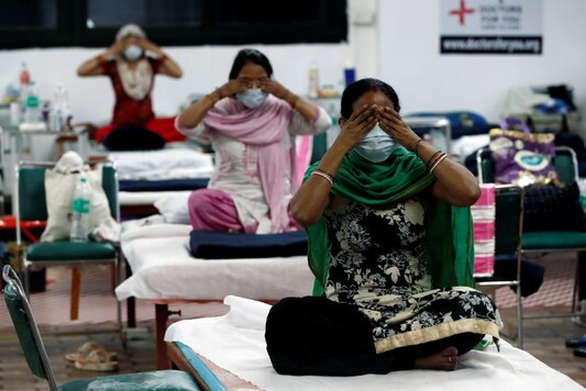 People suffering from the coronavirus disease (COVID-19) perform yoga inside a care centre for COVID-19 patients at an indoor sports complex in New Delhi. (Image: Reuters)