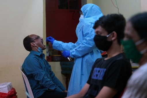 A healthcare worker wearing a protective gear takes swab from a man to test for the coronavirus disease (COVID-19) as others wait for their turn.  REUTERS/Hemanshi Kamani - RC2NZH93YPGV