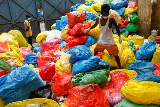 A waste collector walks over disposed medical waste bags inside a rubbish dump outside a hospital, during the coronavirus disease (COVID-19) outbreak, in New Delhi, India, July 17, 2020. REUTERS/Adnan Abidi.