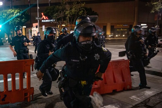 Police chase after protesters who refused to disperse at a protest on Saturday, July 25, 2020, in Oakland, Calif. Protesters in California set fire to a courthouse, damaged a police station and assaulted officers after a peaceful demonstration intensified late Saturday, Oakland police said. (AP Photo/Christian Monterrosa)