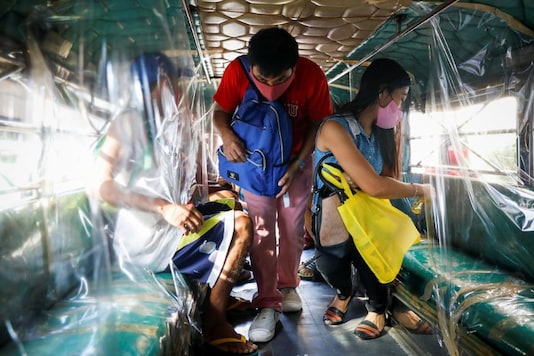 A passenger wearing a mask for protection against the coronavirus disease (COVID-19) boards the jeepney, while another sprays disinfectant on her seat, in Quezon City, Metro Manila, Philippines. (Image: Reuters)
