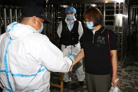A worker in protective suit measures the body temperature of a woman at the entrance to a residential compound, following the coronavirus disease (COVID-19) outbreak in Urumqi, Xinjiang Uighur Autonomous Region, China early July 28, 2020. Picture taken July 28, 2020. (cnsphoto via REUTERS)