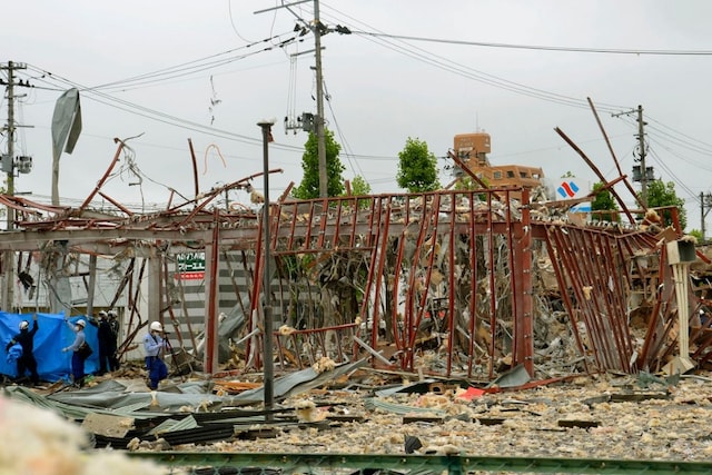 Investigators work near a damaged building following an explosion in Koriyama, Fukushima prefecture, northern Japan Thursday, July 30, 2020. At least more than a dozen people were injured and being taken to hospitals after a sudden explosion blew off walls, windows and debris in the neighborhood. (Kyodo News via AP)