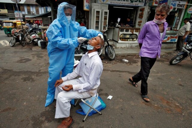 A healthcare worker wearing personal protective equipment (PPE) takes a swab from a man to test him for the coronavirus disease (COVID-19) in a street. (REUTERS/Amit Dave/Files)