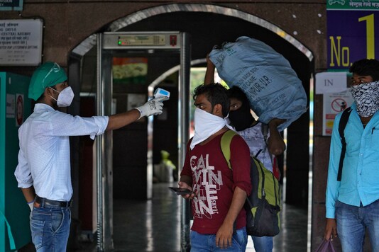 A worker checks a traveller's temperature at Dadar Railway Station. (Reuters)