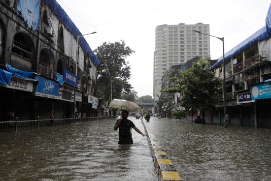 A man wades through a water logged street during heavy rain in Mumbai. (AP)