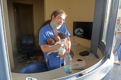 Image  of the nurse holding babies and attending phone calls.