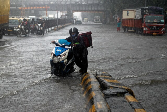 A delivery boy moves his scooter through a waterlogged road in Mumbai. (Reuters)