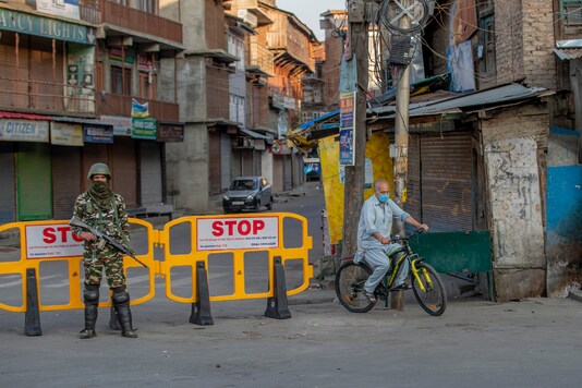 A Kashmiri cycles past a barricade set up as road blockade as a paramilitary soldier stands guard on the first anniversary of the Centre’s decision to revoke J&K’s special status, in Srinagar(AP Photo/Dar Yasin)