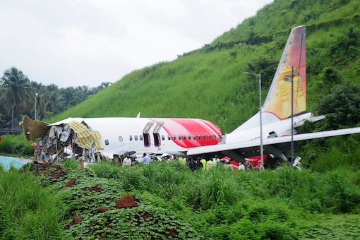 Officials stand on the debris of the Air India Express flight that skidded off a runway in Kozhikode, on Saturday. (AP)