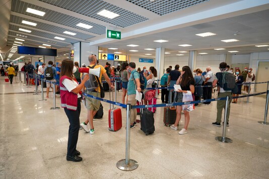 Passengers arriving in Rome from four Mediterranean countries receive instructions by airport staff, right, as they line up with their suitcases at Rome's Leonardo da Vinci airport to be immediately tested for COVID-19, Sunday, Aug.16, 2020. (AP Photo/Andrew Medichini)