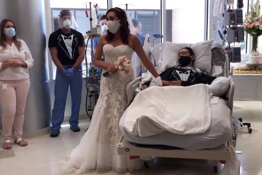 With face masks, bride and groom took their wedding vows in the hospital. With face masks, bride and groom took their wedding vows in the hospital.