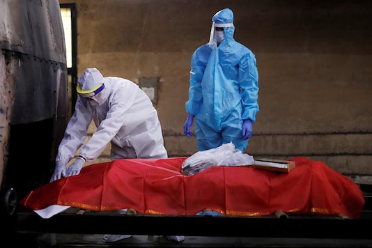 Relatives wearing personal protective equipment (PPE) pay last respect to a man, who died due to the coronavirus disease (COVID-19), before his cremation, at a crematorium in New Delhi. (Reuters)