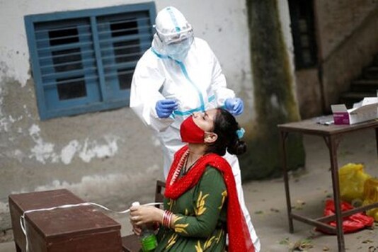 A health worker in personal protective equipment (PPE) collects a sample using a swab from a person at a school which was turned into a centre to conduct tests for the coronavirus disease (COVID-19), amidst the spread of the disease, in New Delhi.
