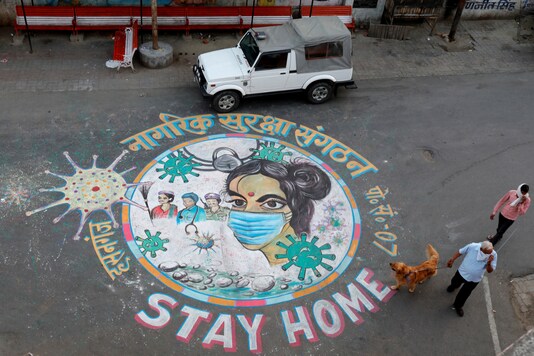 A man walks his dog past graffiti on a road to raise awareness about staying home during an extended national lockdown to curb the spread of the coronavirus disease (COVID-19) in Lucknow.  (Reuters)