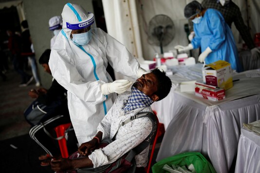 A healthcare worker wearing personal protective equipment (PPE) takes a swab from a migrant worker, who returned to Delhi from his native state, for a rapid antigen test at a bus terminal, amidst the coronavirus disease (COVID-19) outbreak in New Delhi, India, August 17, 2020. REUTERS/Adnan Abidi