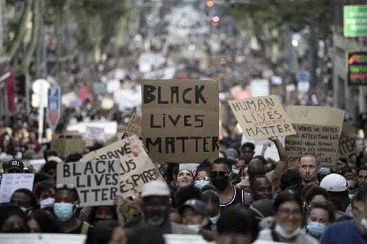 In this representative image, a protester looks up at a sign that reads 