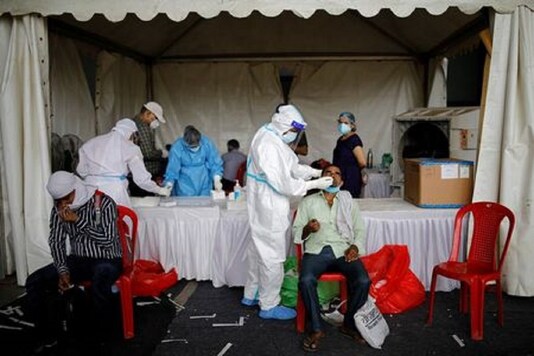 A healthcare worker wearing personal protective equipment (PPE) takes a swab from a migrant worker, who returned to Delhi from his native state, for a rapid antigen test at a bus terminal, amidst the coronavirus disease (COVID-19) outbreak in New Delhi, India, August 17, 2020. (Reuters)