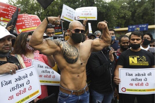 A member of Indian Gym's Welfare Federation flexes his muscles as they block a road during a protest in New Delhi, India, Friday, Aug. 28, 2020. The protestors demanded that the Delhi government allow them to open their gymnasium, which have been closed for the last six months as a precaution against the coronavirus pandemic. (AP Photo/Manish Swarup)