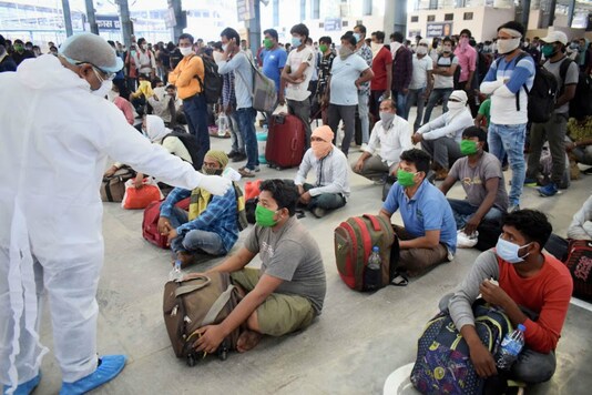 A health official checks temperature of people waiting for a train in Prayagraj. (PTI File)