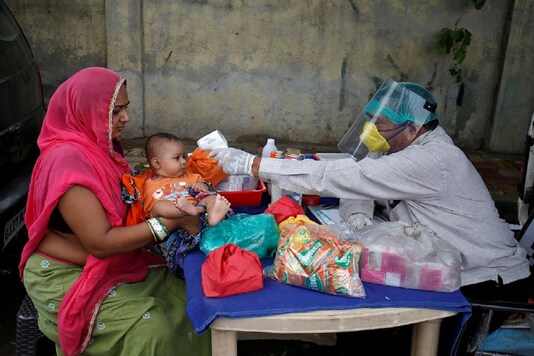 A doctor wearing a protective face shield uses an infrared thermometer to measure the temperature of a child at his mobile health clinic, after his clinic and its adjoining areas were declared a micro-containment zone, after authorities eased lockdown restrictions that were imposed to slow the spread of the coronavirus disease (COVID-19), in Ahmedabad, India, June 15, 2020. REUTERS/Amit Dave/File Photo