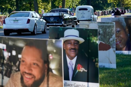 A procession of vehicles drive past photos of Detroit victims of COVID-19, on Belle Isle in Detroit. Families have a chance to take one last public look at their lost loved ones in the nation's first citywide memorial to honor victims of the pandemic. Credits: AP