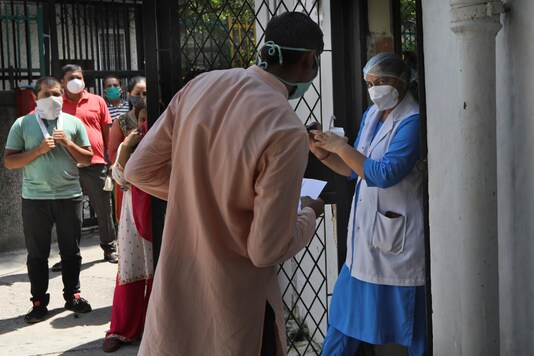 A health worker explains the operation of an oximeter to an asymptomatic person who tested positive for Covid-19 at a local Delhi government dispensary on September 1, 2020 (AP Photo / Manish Swarup).