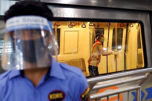 A worker wearing a face shield and mask cleans inside a train at a Delhi Metro station ahead of the restart of its operations, amidst the spread of coronavirus disease (COVID-19), in New Delhi, India, September 3, 2020. REUTERS/Adnan Abidi

