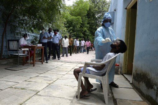 Residents queue up to register their names as a health worker collects a swab sample to test for coronavirus. (AFP)