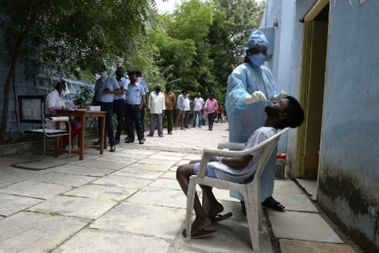Residents queue up to register their names as a health worker collects a swab sample to test for coronavirus. (AFP)