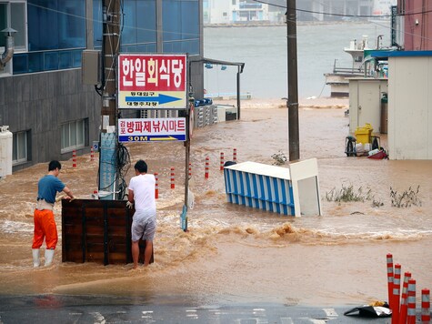 Men stand on a street submerged by typhoon Haishen in Gyeongju, South Korea, September 7, 2020.    Yonhap via REUTERS