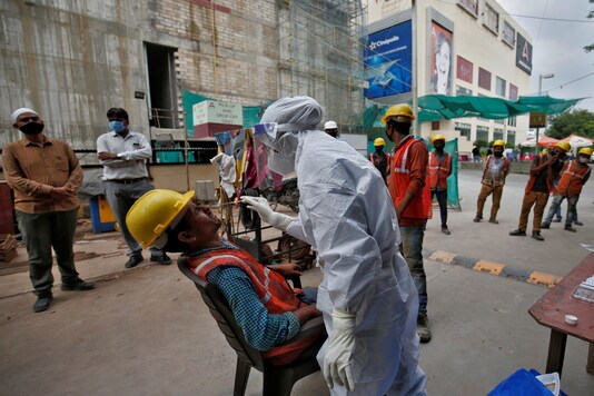 A healthcare worker wearing personal protective equipment (PPE) takes a swab from a construction worker for a rapid antigen test at a construction site, amid the coronavirus disease (COVID-19) outbreak, in Ahmedabad.