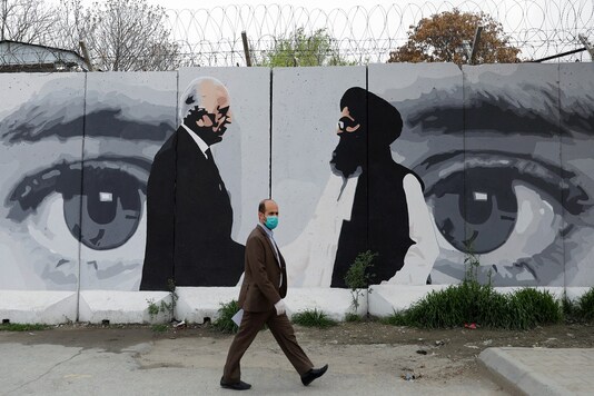 An Afghan man walks past a wall painted with photo of Zalmay Khalilzad, US envoy for peace in Afghanistan, and Mullah Abdul Ghani Baradar, the leader of the Taliban delegation, in Kabul. (File photo: Reuters)
