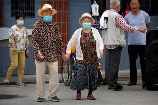 An elderly couple wearing face masks to protect against the coronavirus walks at a public park in Beijing, 