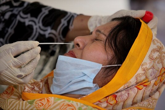 A health worker collects a swab sample from a teacher to test for the coronavirus at a school ahead of its reopening, in Karachi, Pakistan.  (AP Photo/Fareed Khan)