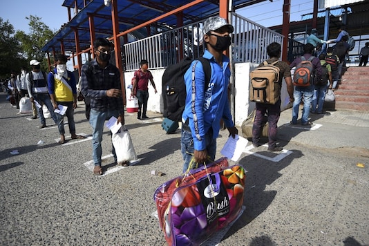 Migrant workers and their family members queue up outside a railway station to board a Bihar-bound Shramik Express train, in Faridabad on May 15, 2020. (AFP)