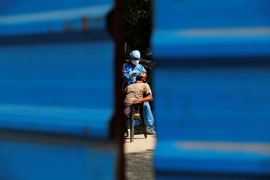 A healthcare worker wearing personal protective equipment (PPE) takes a swab from a migrant laborer for a rapid antigen test at the site of an under-construction residential complex amidst a coronavirus disease (COVID-19) outbreak in New Delhi. (Image: Reuters)