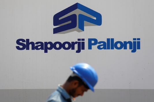 A construction worker walks past a hoarding of Shapoorji Pallonji Group on the outskirts of Mumbai. (Reuters file) A construction worker walks past a hoarding of Shapoorji Pallonji Group on the outskirts of Mumbai. (Reuters file)