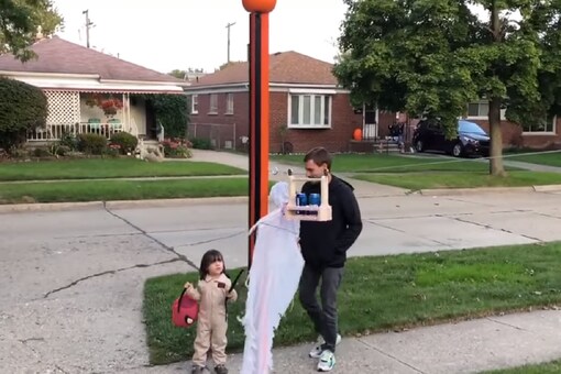 The video shows a child taking trick or treat gift from the woman who is handling a zipline. 