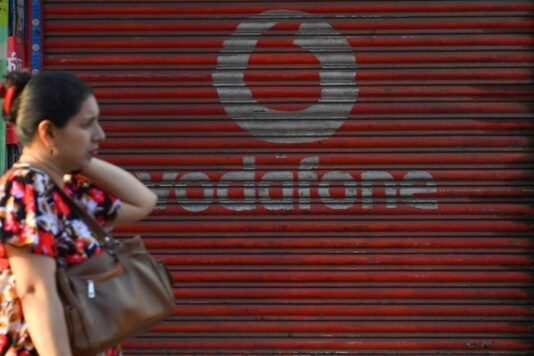 A pedestrian passes a store displaying an advertisement for the telecommunications company Vodafone in Mumbai.  (AFP)