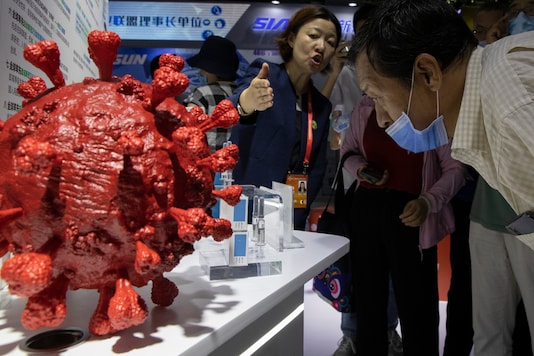 An employee answers questions from the public near samples of a Covid-19 vaccine produced by Sinopharm subsidiary CNBG during a trade fair in Beijing on September 6, 2020. (AP Photo/Ng Han Guan)