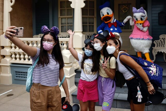 Visitors wearing face masks pose as they take a selfie with Disney characters Donald Duck and Daisy Duck during the reopening day of Disneyland to the public, after a second closure due to the coronavirus disease (COVID-19) outbreak, in Hong Kong, China, September 25, 2020. REUTERS/Tyrone Siu - RC2I5J9FQG70