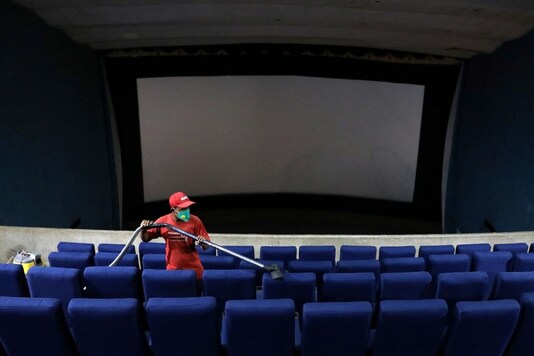 A worker cleans seats at Kolkata's Navina cinema hall that was closed following the coronavirus lockdown. (Reuters)