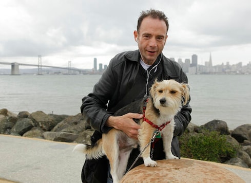FILE - This May 16, 2011 photo shows Timothy Ray Brown with his dog, Jack, on Treasure Island in San Francisco.  Brown, who was known for years as the Berlin patient, had a transplant in Germany from a donor with natural resistance to the AIDS virus. It was thought to have cured Brown's leukemia and HIV. But in an interview Thursday, Sept. 24, 2020,  Brown said his cancer returned last year and has spread widely. His case has inspired scientists to seek more practical ways to try to cure the disease.  (AP Photo/Eric Risberg)