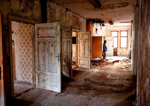 A woman stands in a wrecked and abandoned villa built in 1900 near Eisenach, eastern Germany, Monday, Sept. 21, 2020. Thirty years after Germany was reunited on Oct. 3, 1990, many once-decrepit city centers in the formerly communist east have been painstakingly restored and new factories have sprung up. But many companies and facilities didn't survive the abrupt transition to capitalism inefficient companies found themselves struggling to compete in a market economy, while demand for eastern products slumped and outdated facilities were shut down.  (AP Photo/Michael Probst)