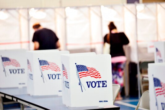 In this Sept. 8, 2020 photo, voting booths are kept socially distant at the Chesterfield, N.H. polling site. A majority of President Donald Trumps supporters plan to cast their ballot on Election Day, while about half of Joe Bidens backers plan to vote by mail. That's according to a new poll from The Associated Press-NORC Center for Public Affairs Research that finds 54% of voters say they will vote before polls open on Nov. 3. (Kristopher Radder/The Brattleboro Reformer via AP) In this Sept. 8, 2020 photo, voting booths are kept socially distant at the Chesterfield, N.H. polling site. A majority of President Donald Trumps supporters plan to cast their ballot on Election Day, while about half of Joe Bidens backers plan to vote by mail. That's according to a new poll from The Associated Press-NORC Center for Public Affairs Research that finds 54% of voters say they will vote before polls open on Nov. 3. (Kristopher Radder/The Brattleboro Reformer via AP)