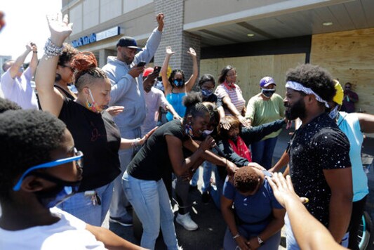 A group prays, Tuesday, June 2, 2020, in Louisville, Ky. near the intersection where David McAtee was killed Sunday evening. McAtee, the owner of a barbecue spot who was known for offering meals to police officers, died while police and National Guard soldiers were enforcing a curfew early Monday amid waves of protests over a previous police shooting. (AP Photo/Darron Cummings)