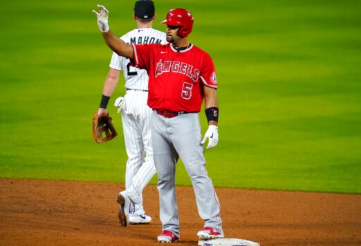 Los Angeles Angels' Albert Pujols, front, gestures to the dugout after reaching second base with an RBI-double as Colorado Rockies second baseman Ryan McMahon heads back to his position in the sixth inning of a baseball game Saturday, Sept. 12, 2020, in Denver. (AP Photo/David Zalubowski)