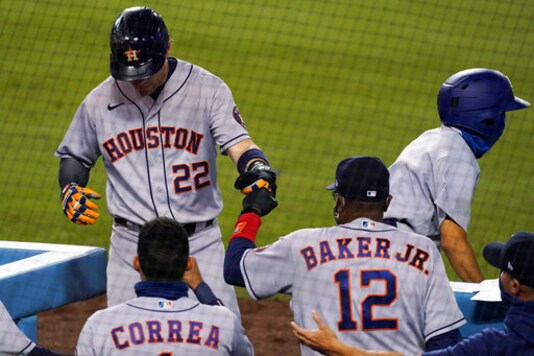 Houston Astros' Josh Reddick, left, returns to the dugout after scoring the tying run during the ninth inning of the team's baseball against the Los Angeles Dodgers at Dodger Stadium on Saturday, Sept. 12, 2020, in Los Angeles. (AP Photo/Ashley Landis)